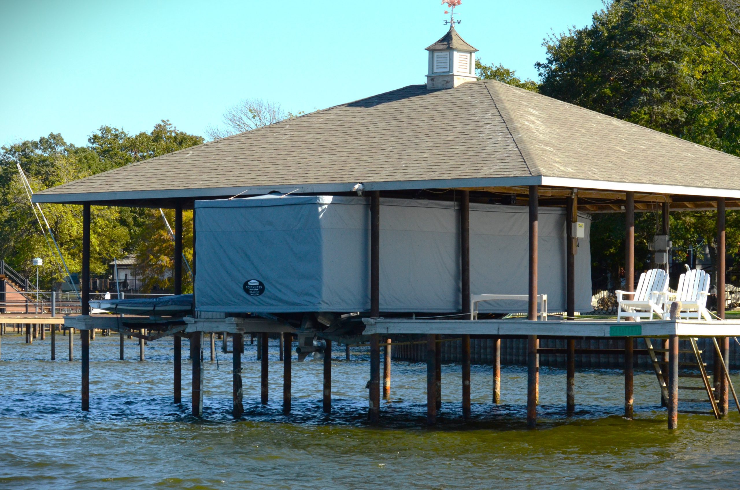 Covered boat inside elevated lakeside boathouse