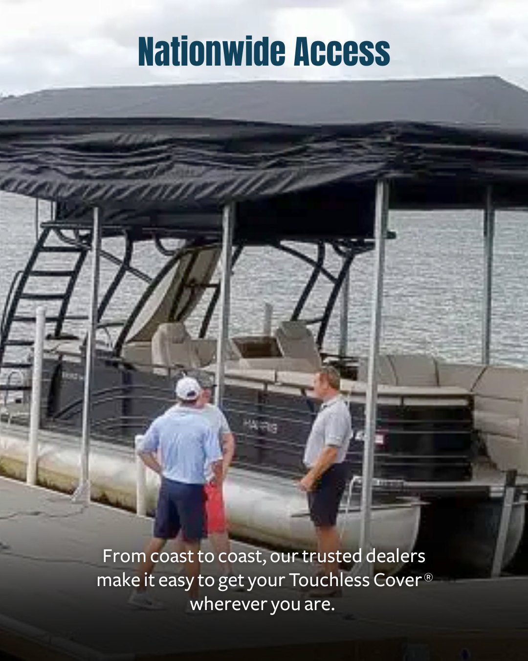 Boat docked beneath a black Touchless Cover® canopy, with three people on the dock and a lakefront backdrop.