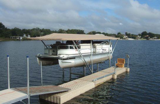 Boat moored at dock with Touchless Cover® under cloudy blue sky