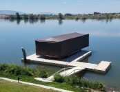 Touchless Boat Cover shielding a docked pontoon boat on a peaceful lake