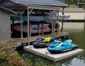 Ski boat cover system shown on dock beside jet skis