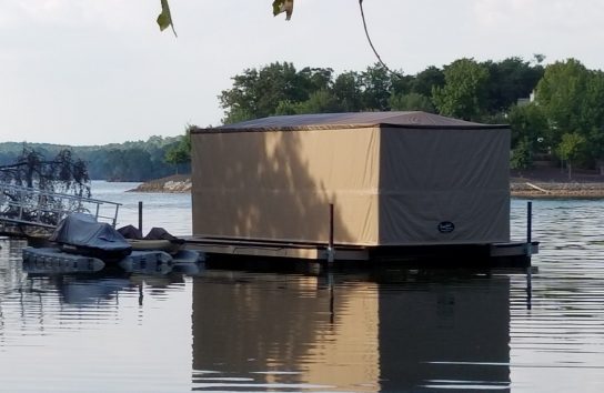 Boat secured to a dock with an automatic cover for extra shelter.