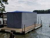 Automatic ski boat cover set up on a dock over water.