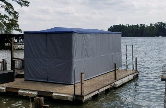 Automatic ski boat cover set up on a dock over water.