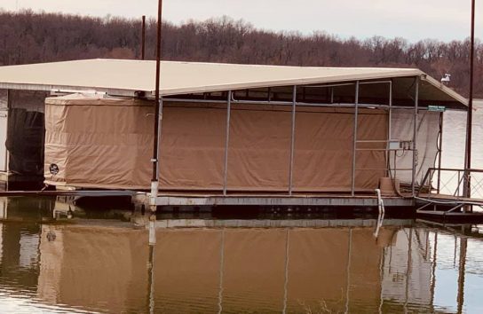Boat house with pontoon boat and Touchless Boat Cover on lake