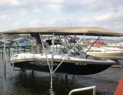 Boat with an automatic ski cover docked beneath protection.