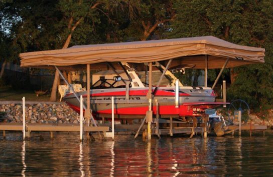Ski boat parked beneath an automatic boat cover on a dock.