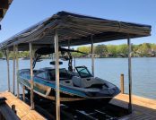 Boat dock with Touchless Automatic Boat Cover and docked wake boat.