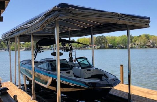 Boat dock with Touchless Automatic Boat Cover and docked wake boat.