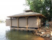 Pontoon boat docked in front of a calm lake with automatic cover