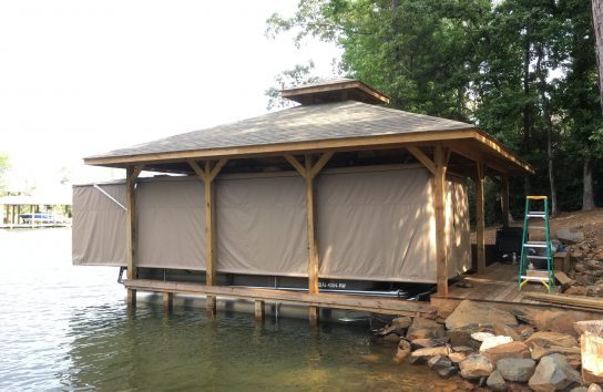 Pontoon boat docked in front of a calm lake with automatic cover