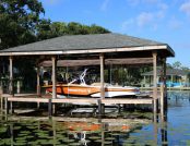 Boat dock featuring an automatic ski boat cover on a boat resting on the dock.