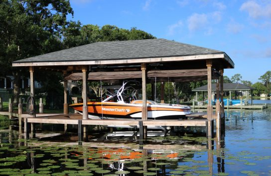 Boat dock featuring an automatic ski boat cover on a boat resting on the dock.