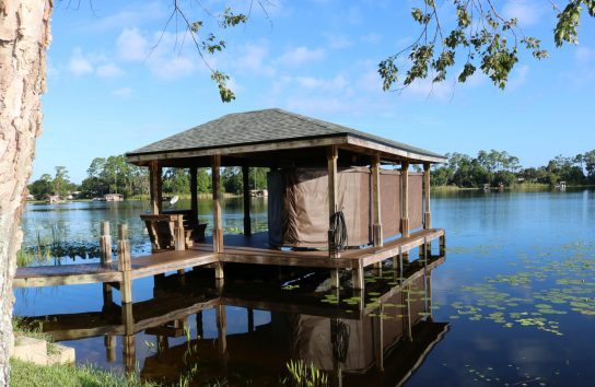 Boat dock with a boat equipped with an automatic ski boat cover, ready for use.