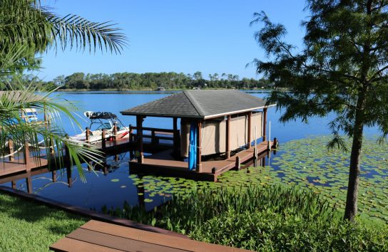 Boat dock showcasing a boat under an automatic ski boat cover, positioned on the dock.