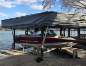 A boat under an automatic boat cover resting on a dock.
