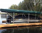 Boat moored at wooden dock with automatic Touchless Boat Cover under clear blue sky