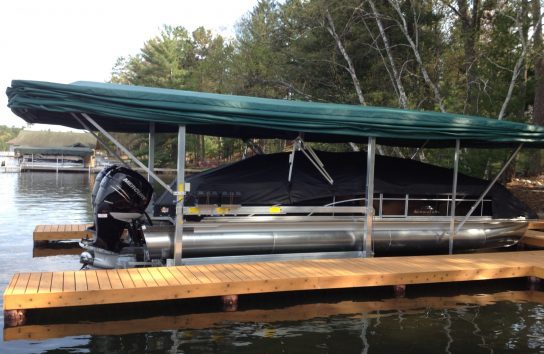 Boat moored at wooden dock with automatic Touchless Boat Cover under clear blue sky