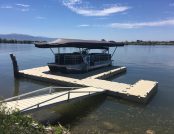 Touchless Boat Cover folded open over a docked pontoon boat on a lake