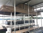 Avalon pontoon boat docked under a roofed dock with a Touchless Automatic Boat Cover
