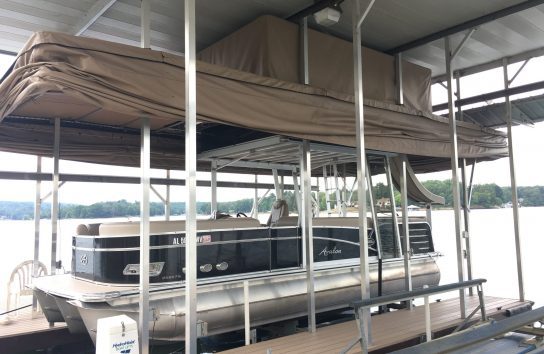 Avalon pontoon boat docked under a roofed dock with a Touchless Automatic Boat Cover