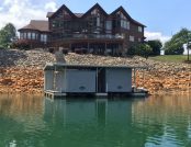 Two pontoon boats docked in front of a mansion, fully covered by Touchless Automatic Boat Covers