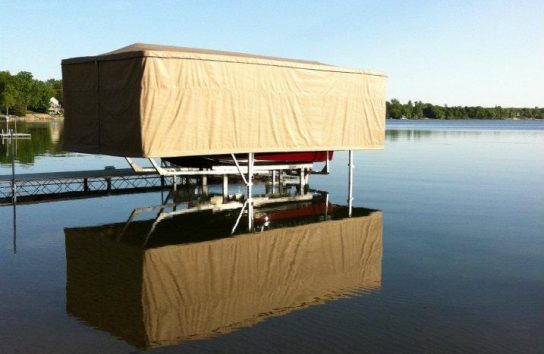 Docked ski boat in the middle of a lake, fully protected by a Touchless Boat Cover on a peaceful afternoon.