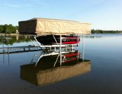 Ski boat docked mid-lake beneath a Touchless Automatic Boat Cover on a quiet afternoon.
