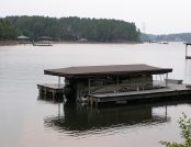 Pontoon boat docked with Touchless Boat Cover retracted overhead
