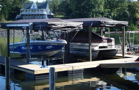 Ski boat and wake boat docked on Lake Wylie with Touchless Automatic Boat Covers ready for remote deployment.