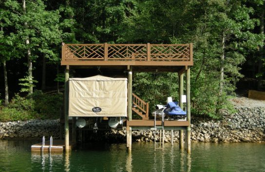 Pontoon boat covered by light brown automatic Touchless Cover® in Southern California boathouse